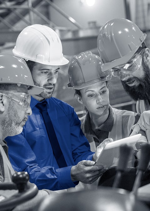 four people in hard hats reading off a tablet